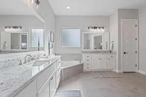a spacious bathroom with a granite countertop sink mirror and bathtub