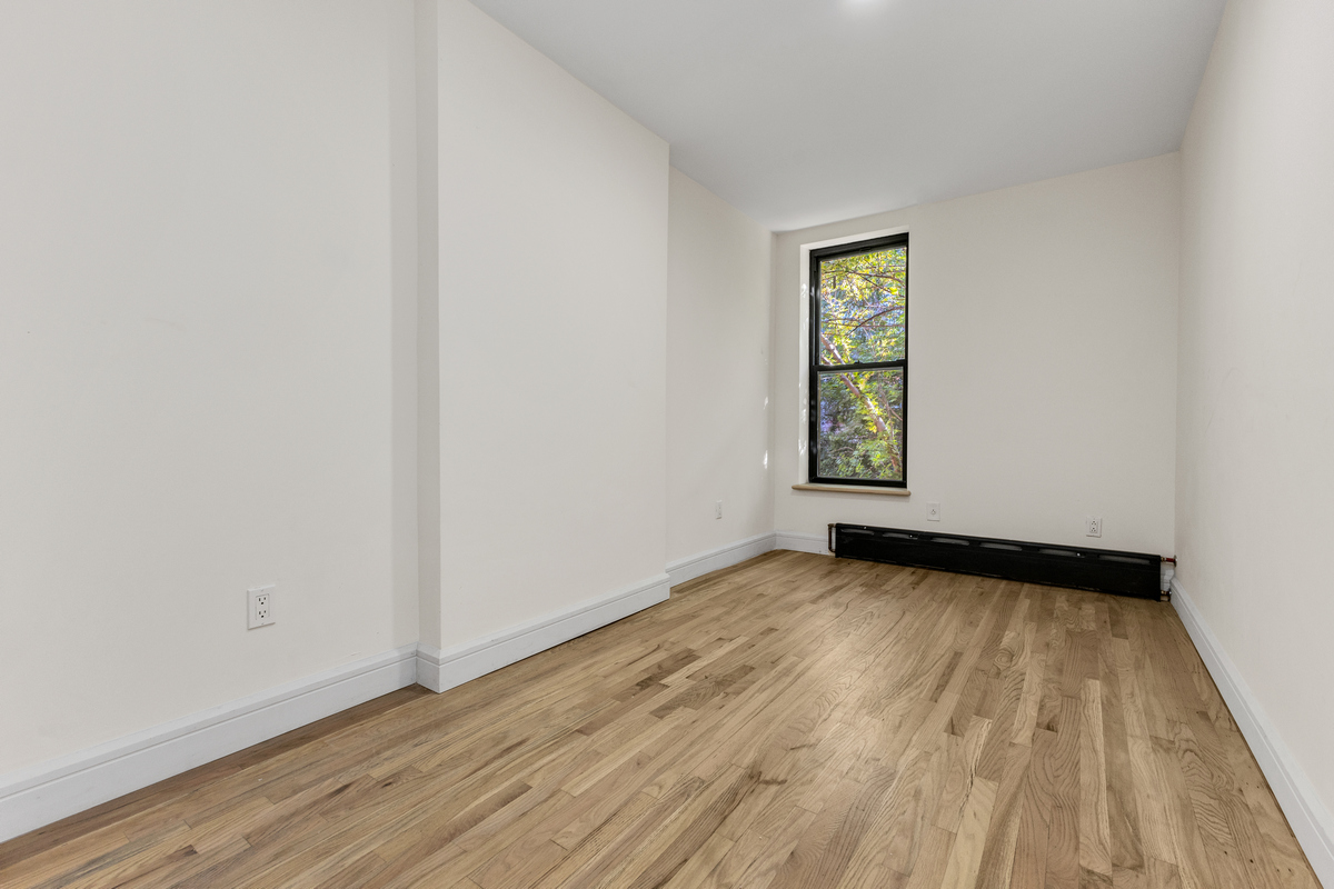 574 Gates Avenue Brooklyn, NY 11221 - Photo 7 of 16 a view of an empty room with wooden floor and a window