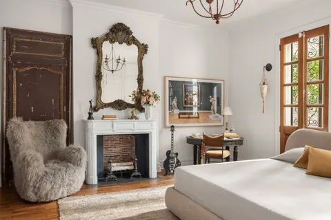 a bedroom with a bed a fireplace and a painting on the wall