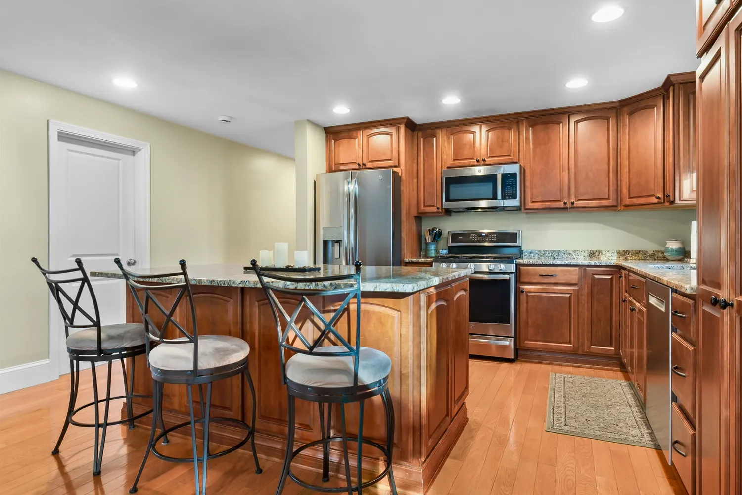a kitchen with stainless steel appliances granite countertop a stove a sink a microwave a dining table and chairs