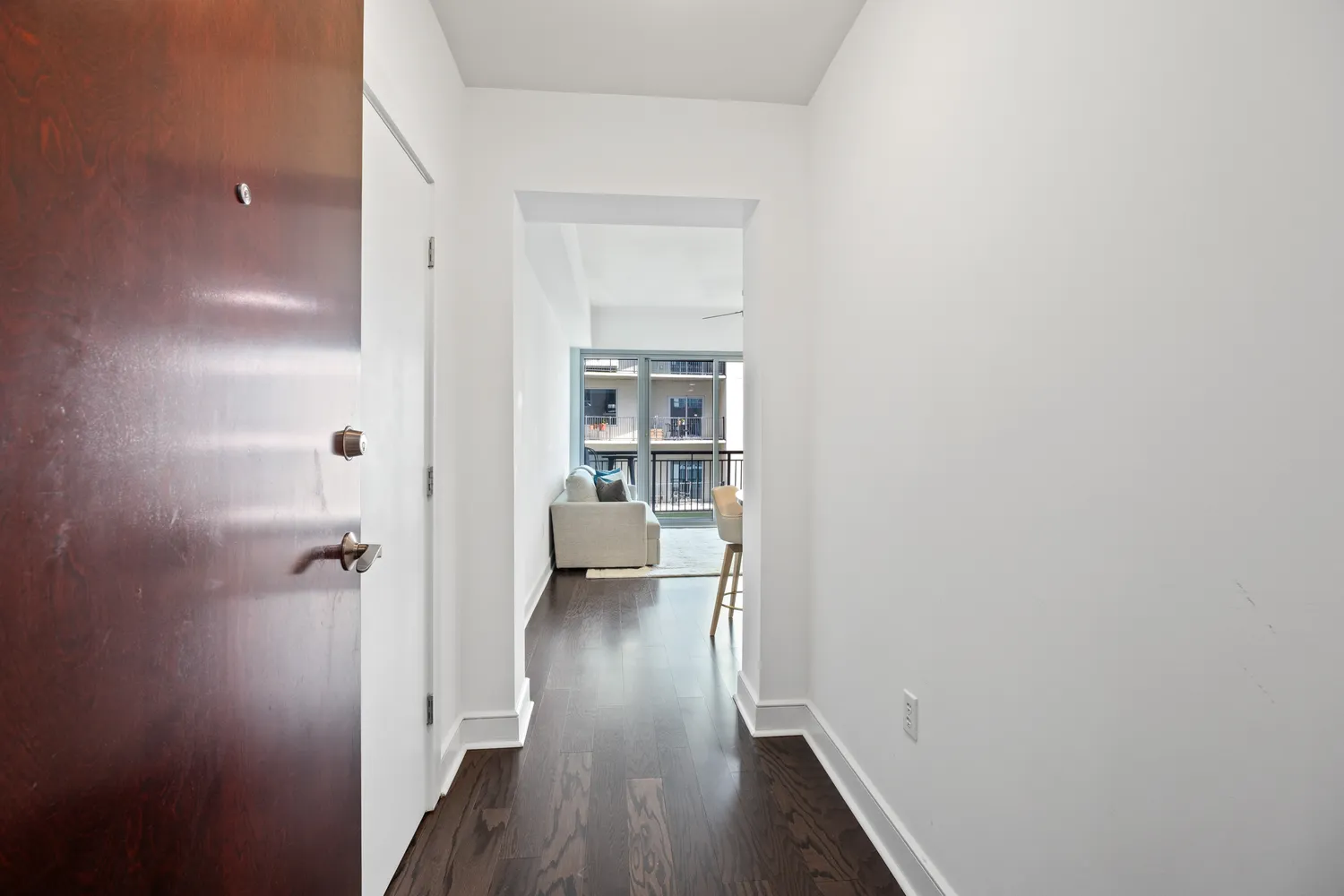 a view of a hallway with wooden floor and a bathroom