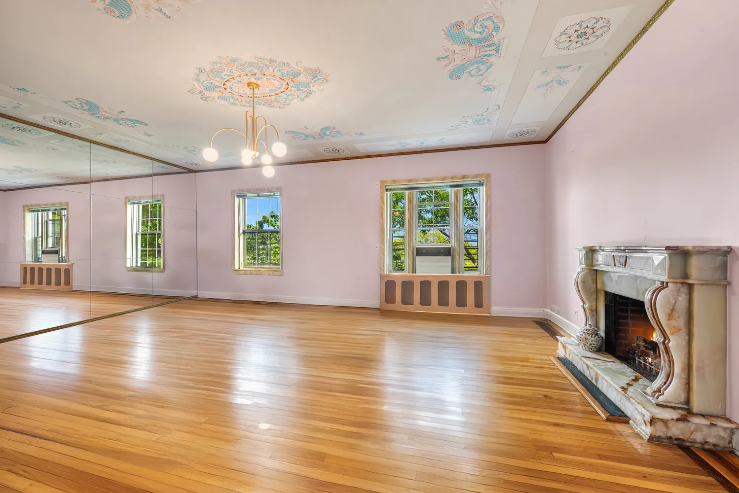 an empty room with wooden floor fireplace and windows