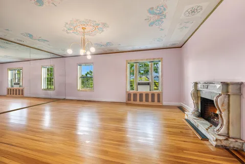 an empty room with wooden floor fireplace and windows