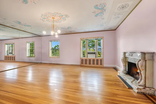 an empty room with wooden floor fireplace and windows