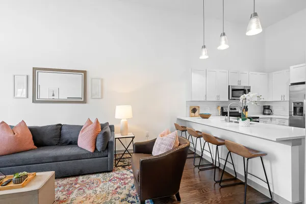 a living room with stainless steel appliances kitchen island a table and chairs
