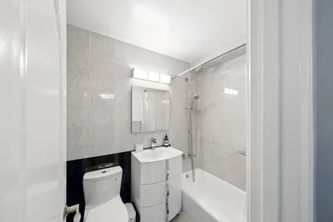 a bathroom with a bathtub shower sink mirror and toilet