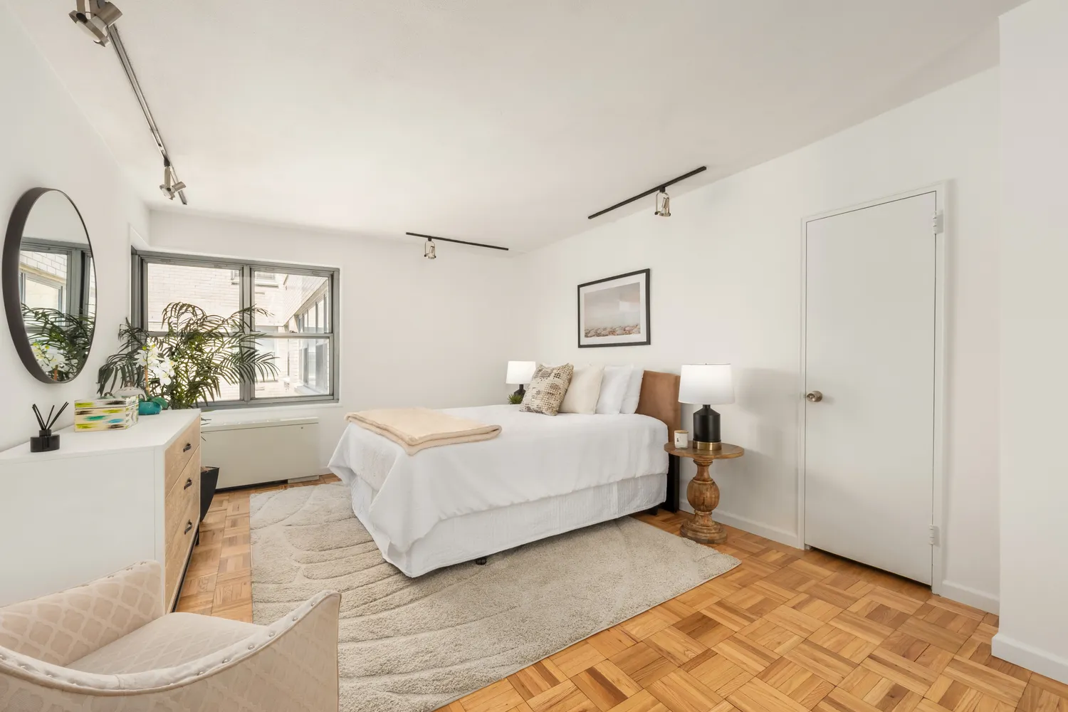 a spacious bedroom with a bed a mirror and a large window