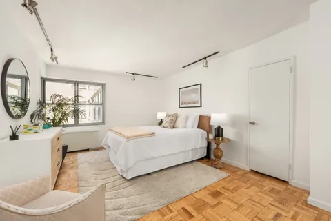 a spacious bedroom with a bed a mirror and a large window