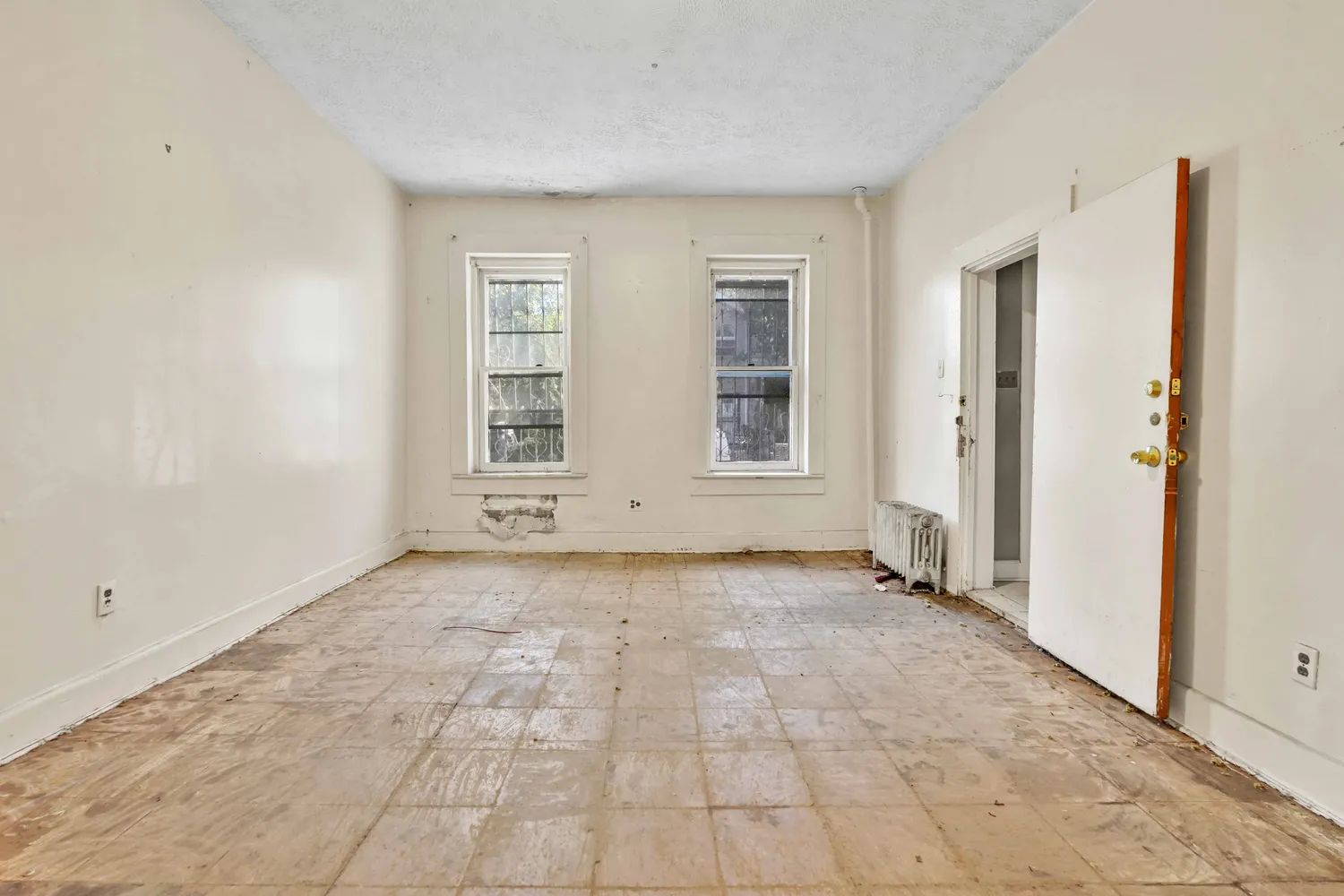 a view of an empty room with wooden floor and windows