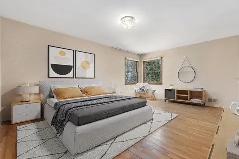 a bedroom with a bed a mirror and a large window with wooden floor
