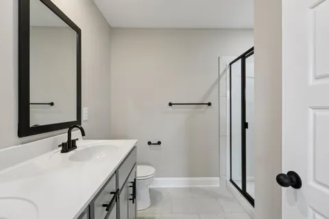 a bathroom with a sink a toilet a mirror and shower