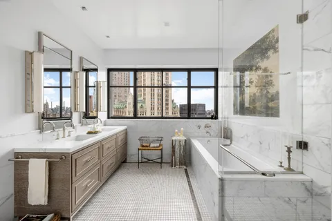 a bathroom with a double vanity sink a large mirror and a bathtub