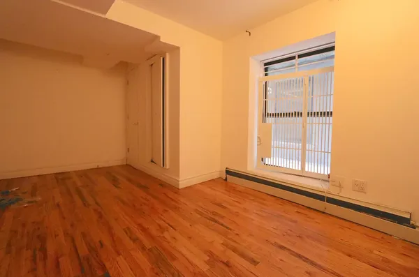 an empty room with wooden floor and a window