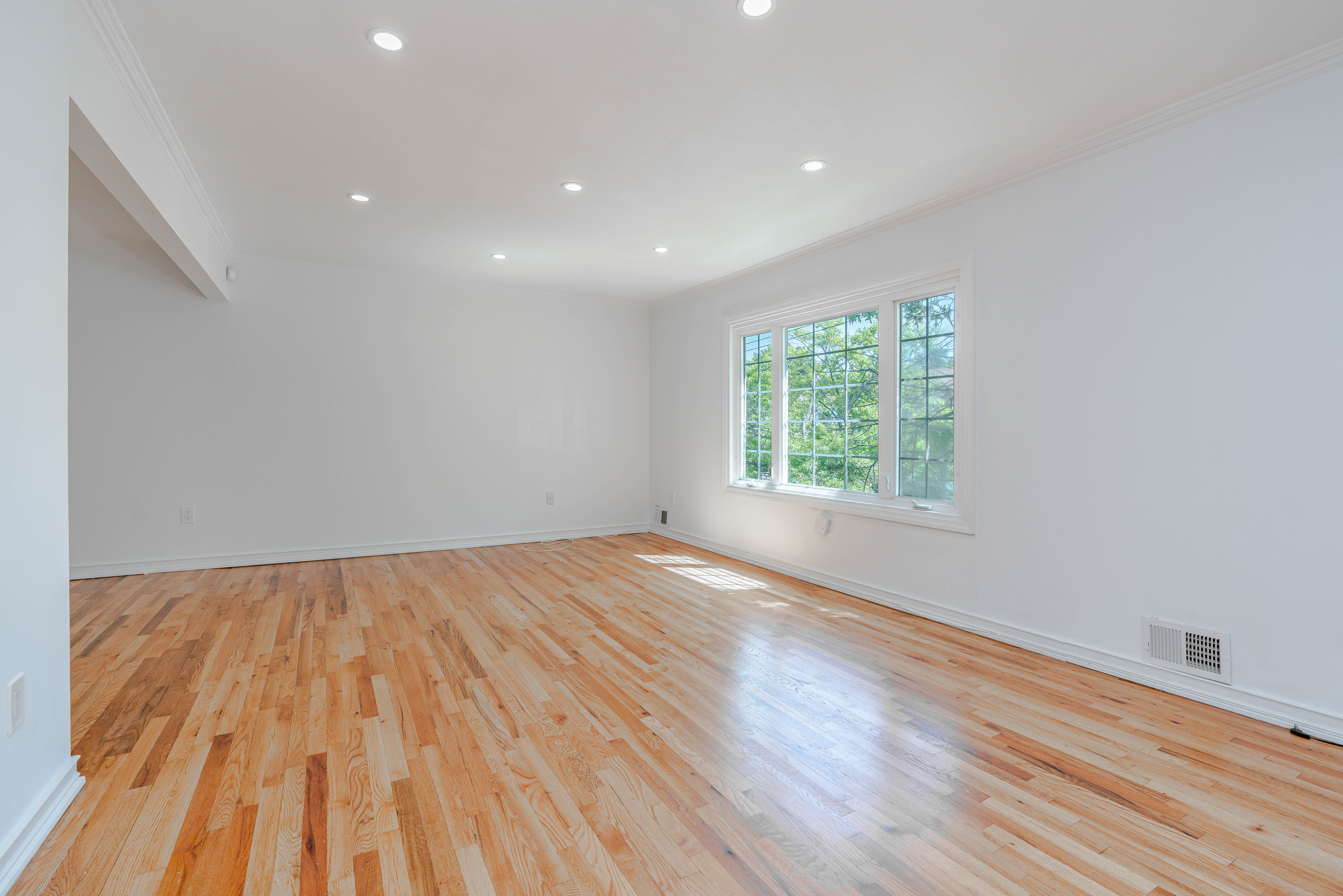 15-80 209th Street, Unit 2 Queens, NY 11360 - Photo 5 of 11 an empty room with wooden floor and windows
