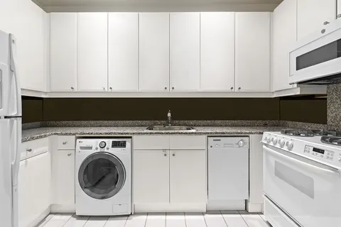 a kitchen with white cabinets and white appliances