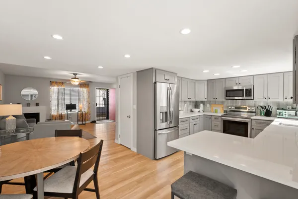 a kitchen with stainless steel appliances kitchen island granite countertop a refrigerator a stove top oven a sink dishwasher and white cabinets with wooden floor