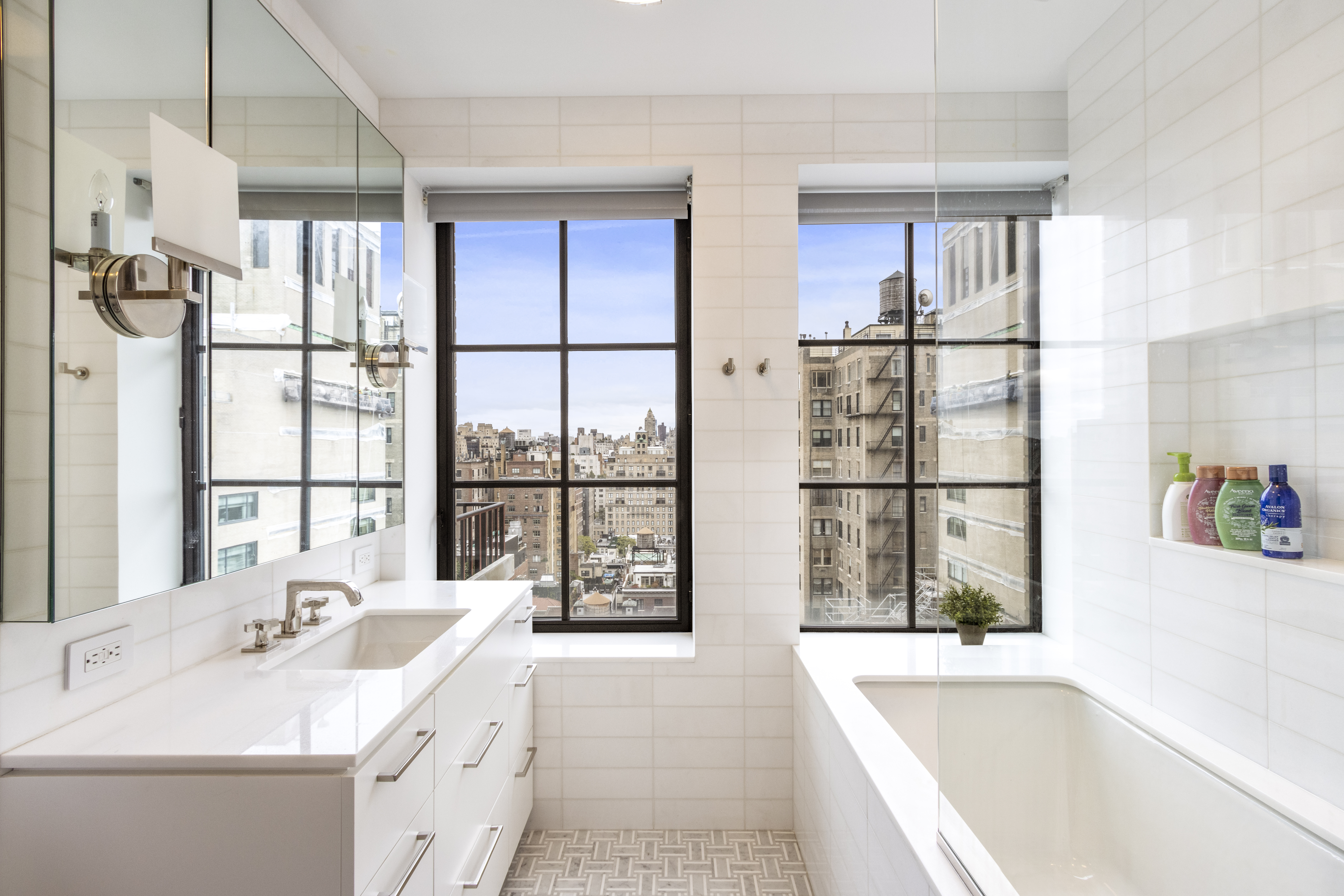 40 East 61st Street, Unit 18A Manhattan, NY 10065 - Photo 11 of 15 a bathroom with a tub sink and large mirror