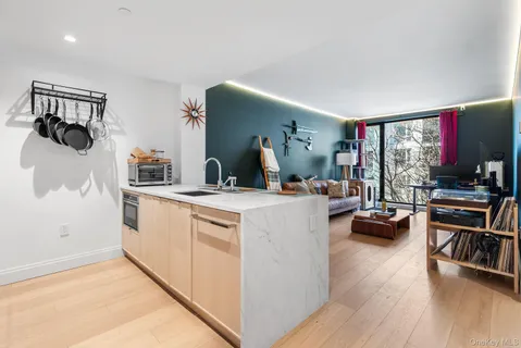 a living room with stainless steel appliances furniture a flat screen tv and a kitchen view