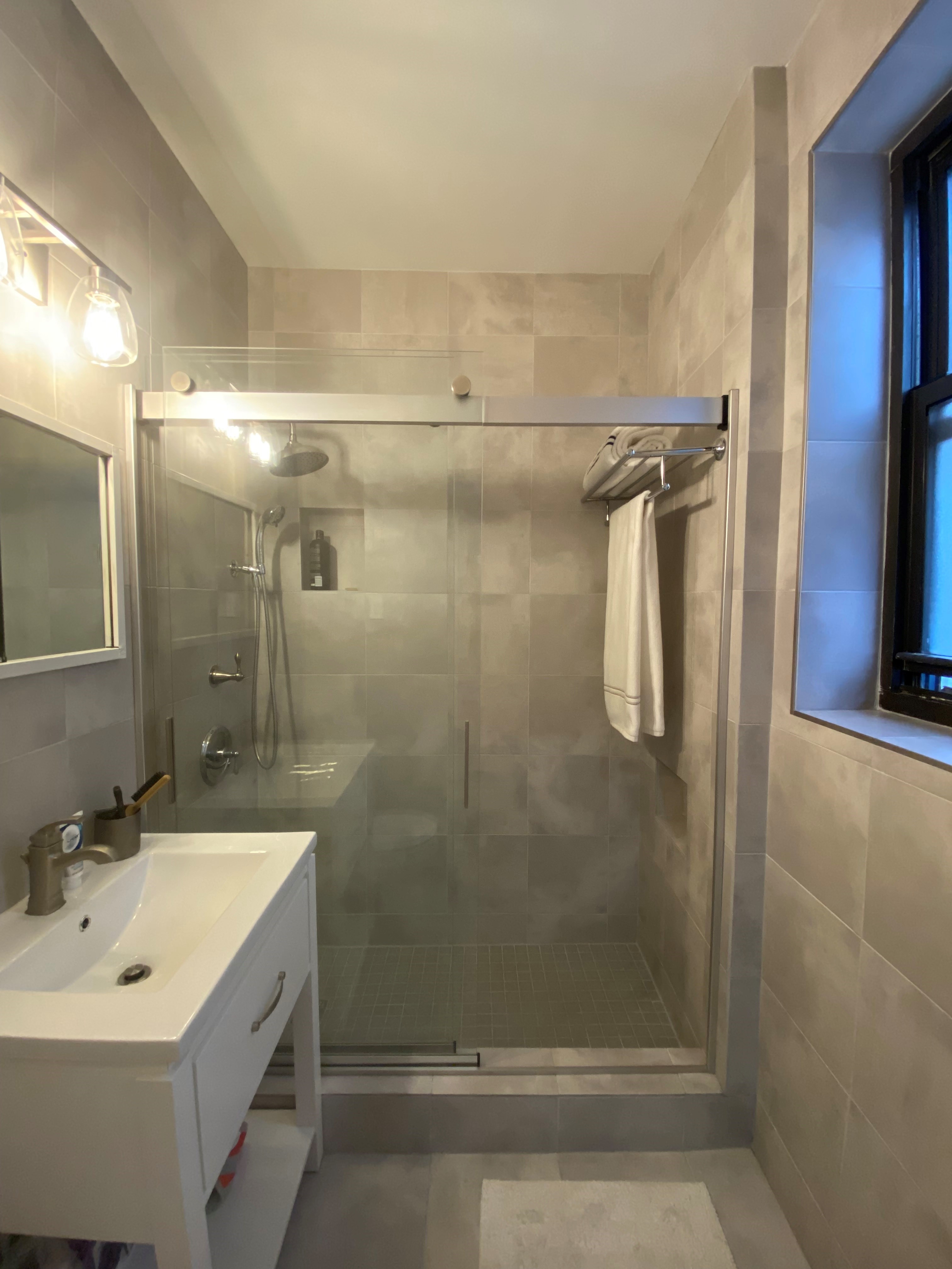 512 East 83rd Street, Unit 2A Manhattan, NY 10028 - Photo 6 of 11 a bathroom with a shower sink vanity and mirror