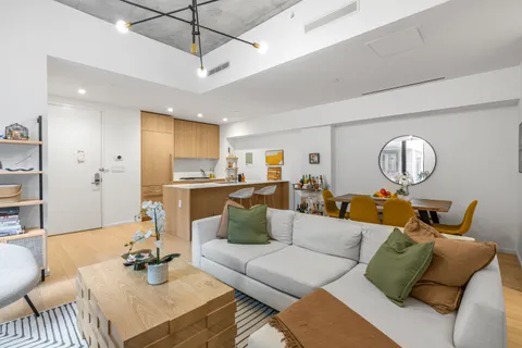 a living room with furniture kitchen view and a chandelier