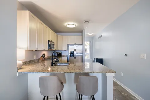 a kitchen with kitchen island granite countertop a table chairs sink and cabinets