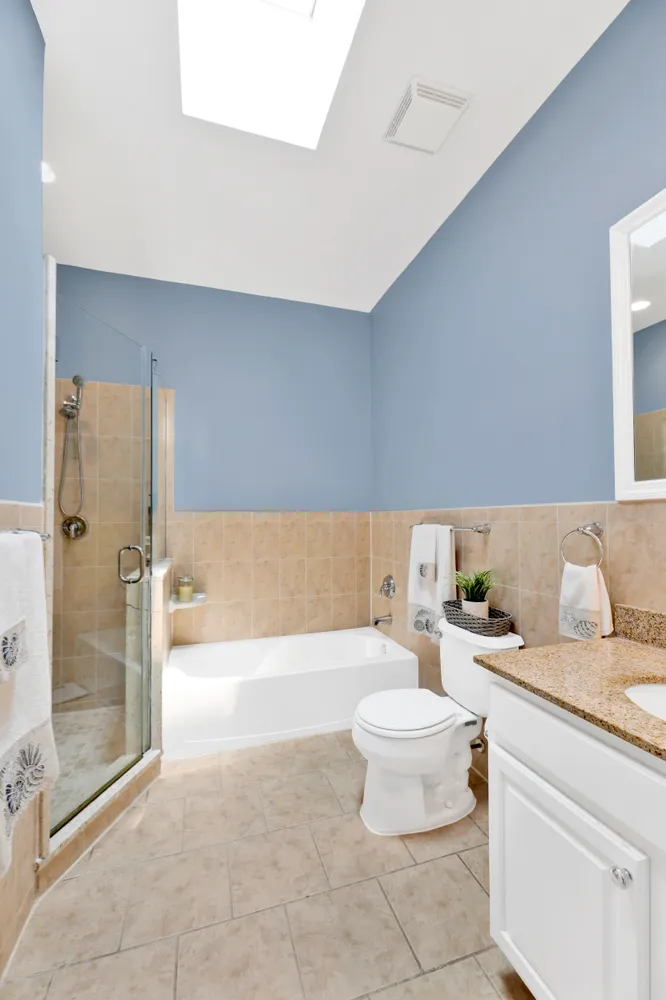 a bathroom with a granite countertop bathtub sink mirror and toilet