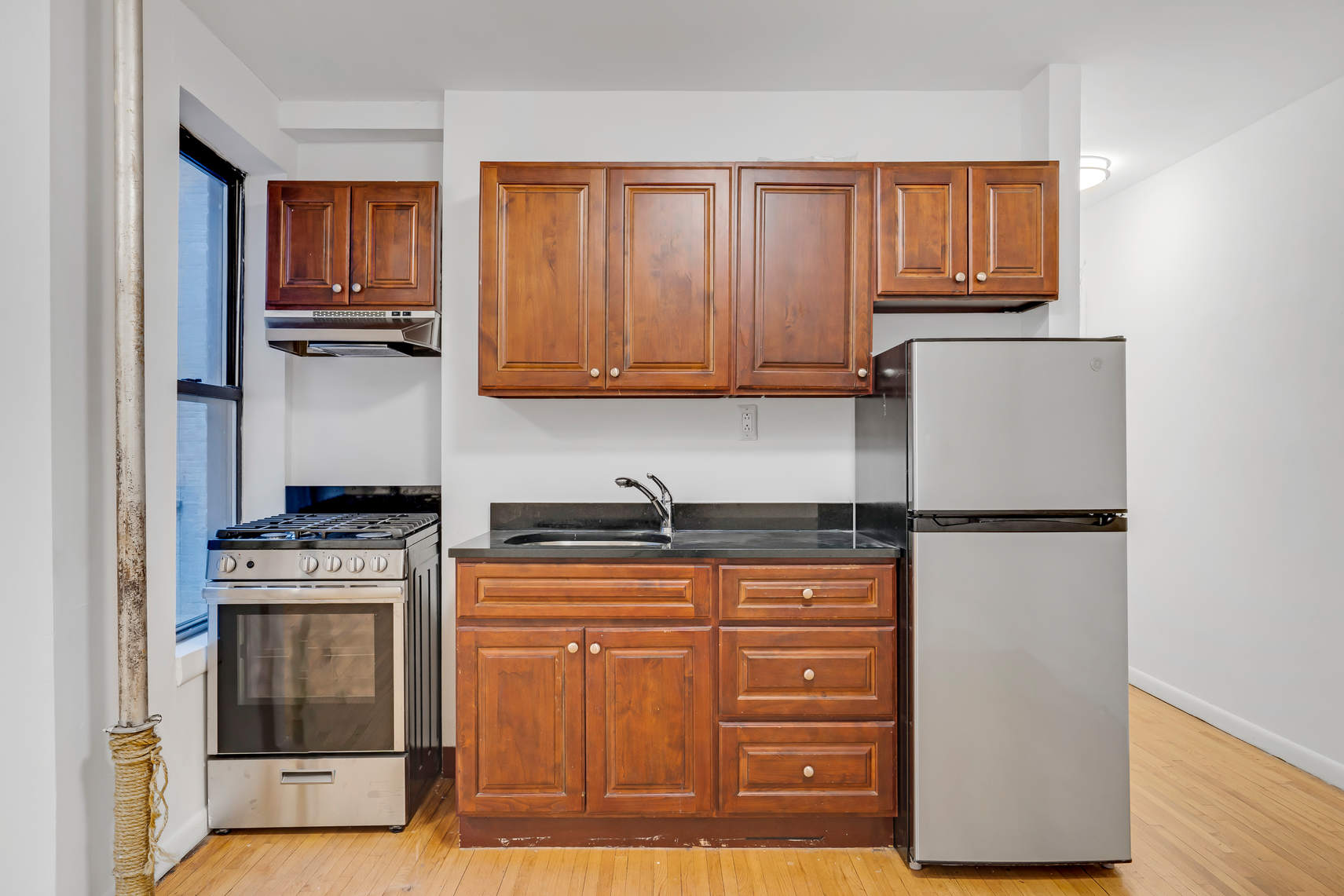 24 East 97th Street, Unit 6 Manhattan, NY 10128 - Photo 6 of 7 a kitchen with granite countertop a refrigerator stove and microwave