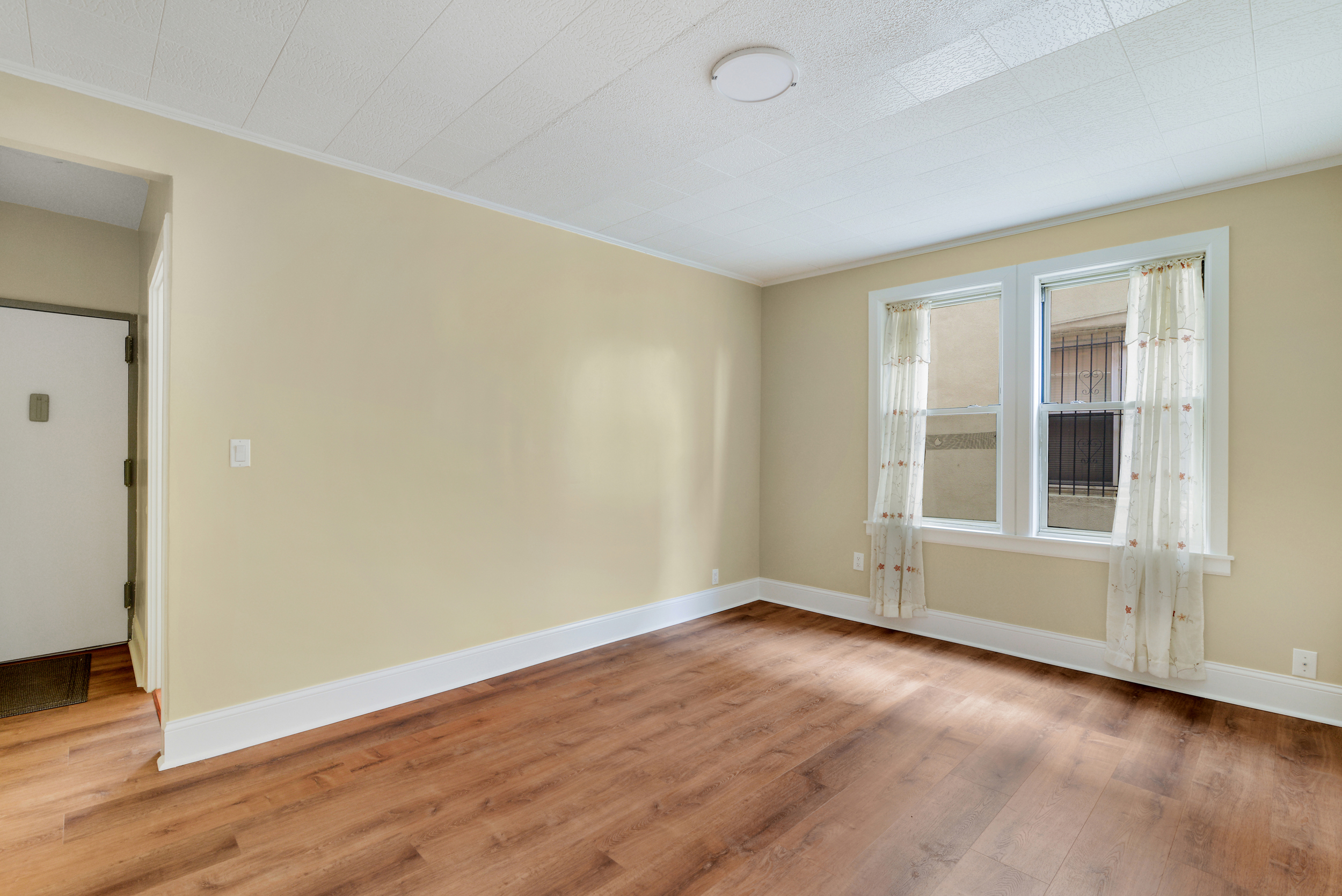 91-11 32nd Avenue, Unit 2 Queens, NY 11369 - Photo 2 of 9 an empty room with wooden floor and windows