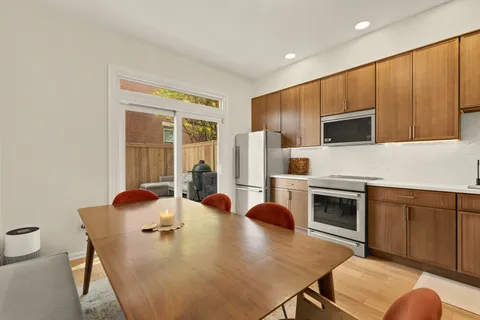 a kitchen with stainless steel appliances granite countertop a stove a refrigerator a oven a sink with a dining table and chairs