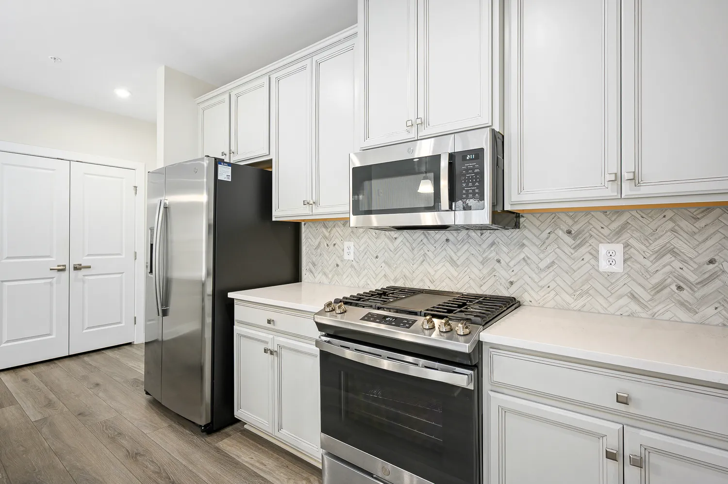 a kitchen with cabinets stainless steel appliances and wooden floor