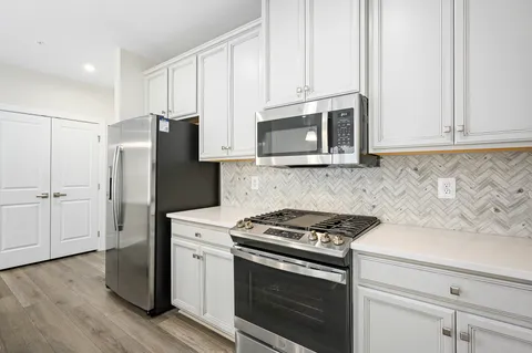 a kitchen with cabinets stainless steel appliances and wooden floor