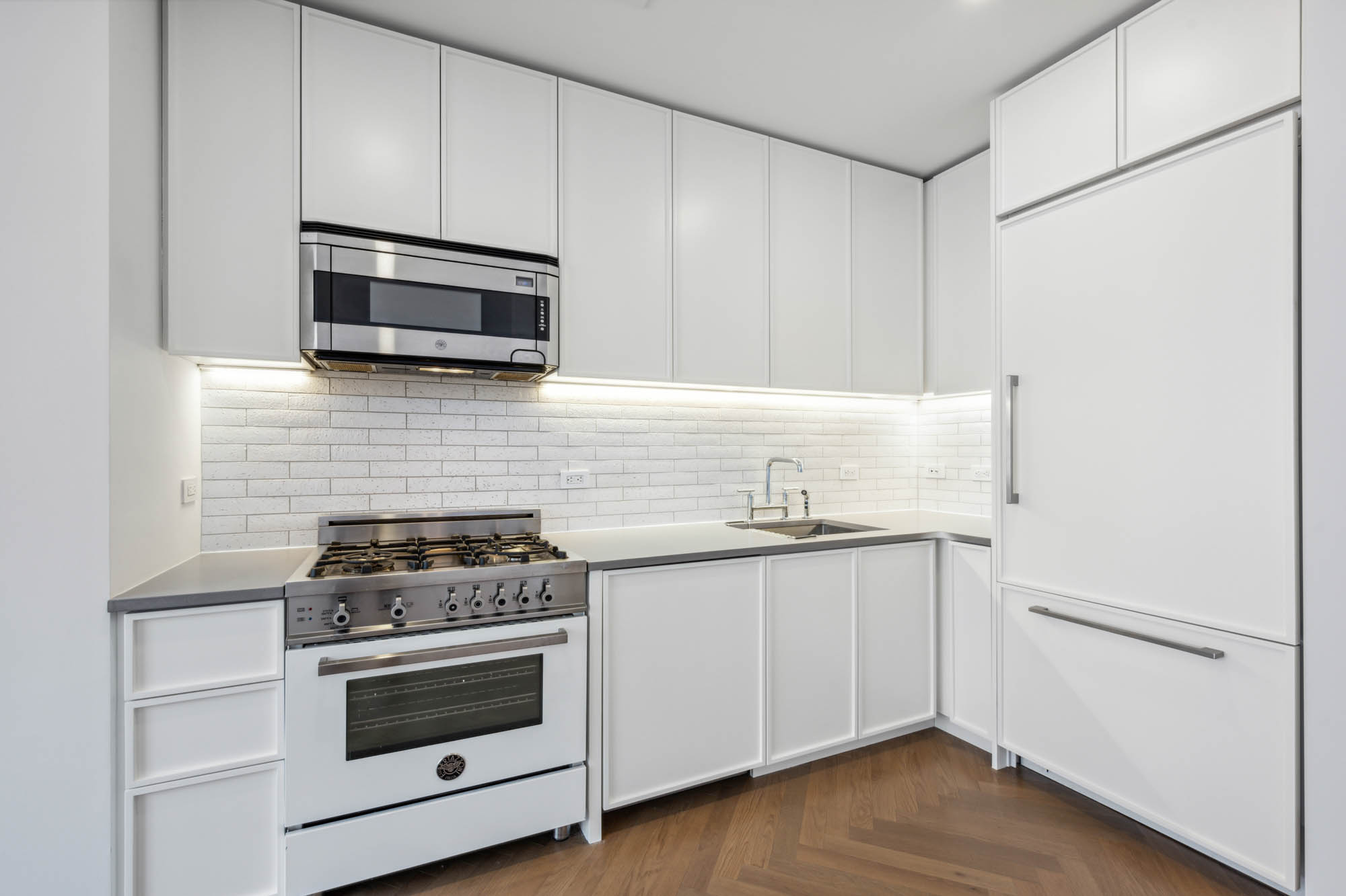 184 Kent Avenue, Unit D512 Brooklyn, NY 11249 - Photo 3 of 11 a kitchen with stainless steel appliances white cabinets and stove top oven