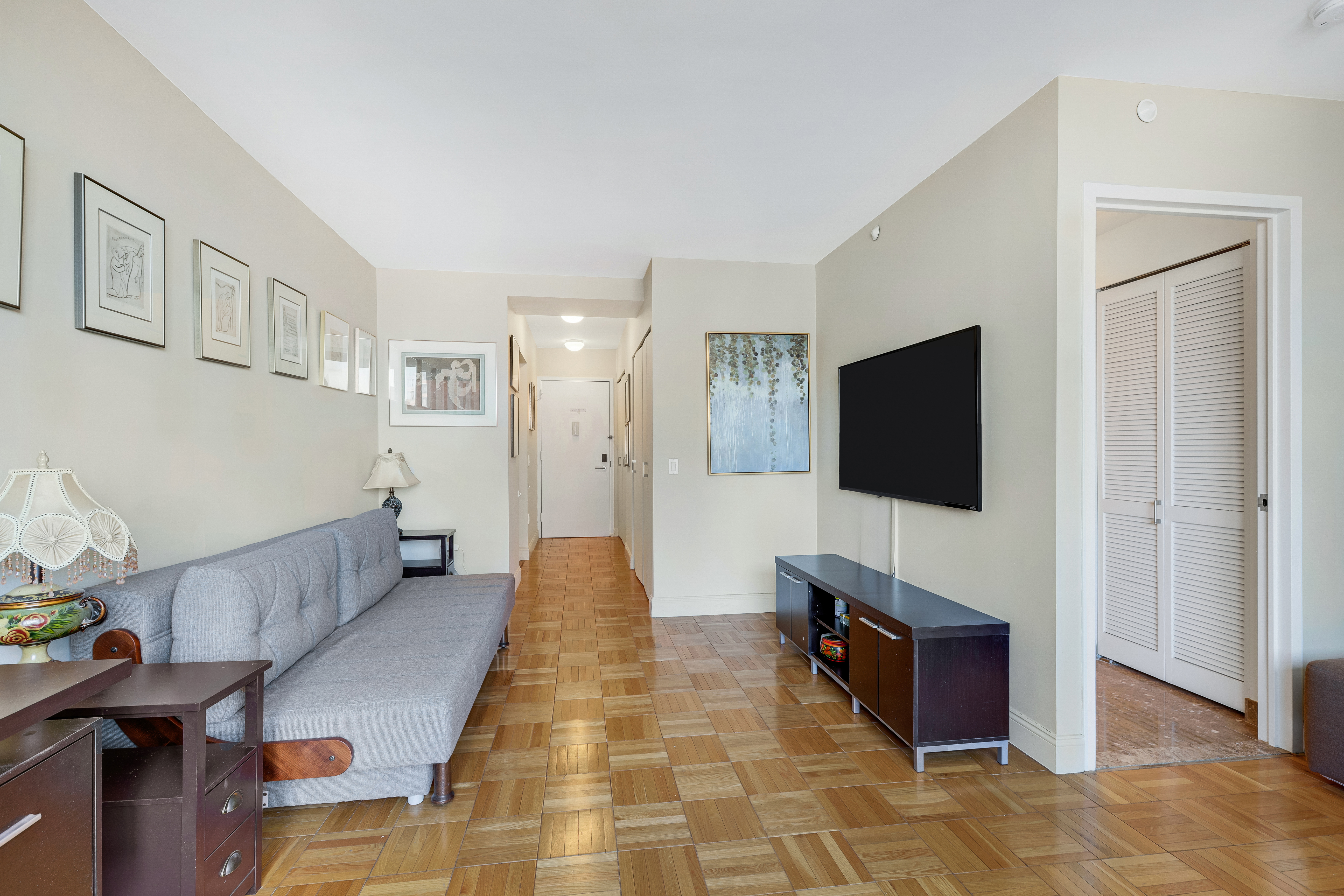 215-217 East 96th Street, Unit 25K Manhattan, NY 10128 - Photo 3 of 16 a living room with furniture and a flat screen tv