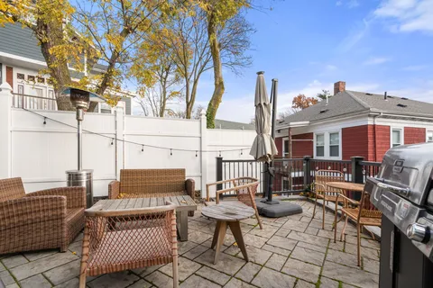 a view of a patio with couches table and chairs and wooden fence