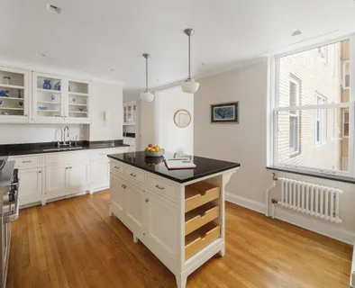 a kitchen with stainless steel appliances granite countertop a stove a sink dishwasher and white cabinets with wooden floor