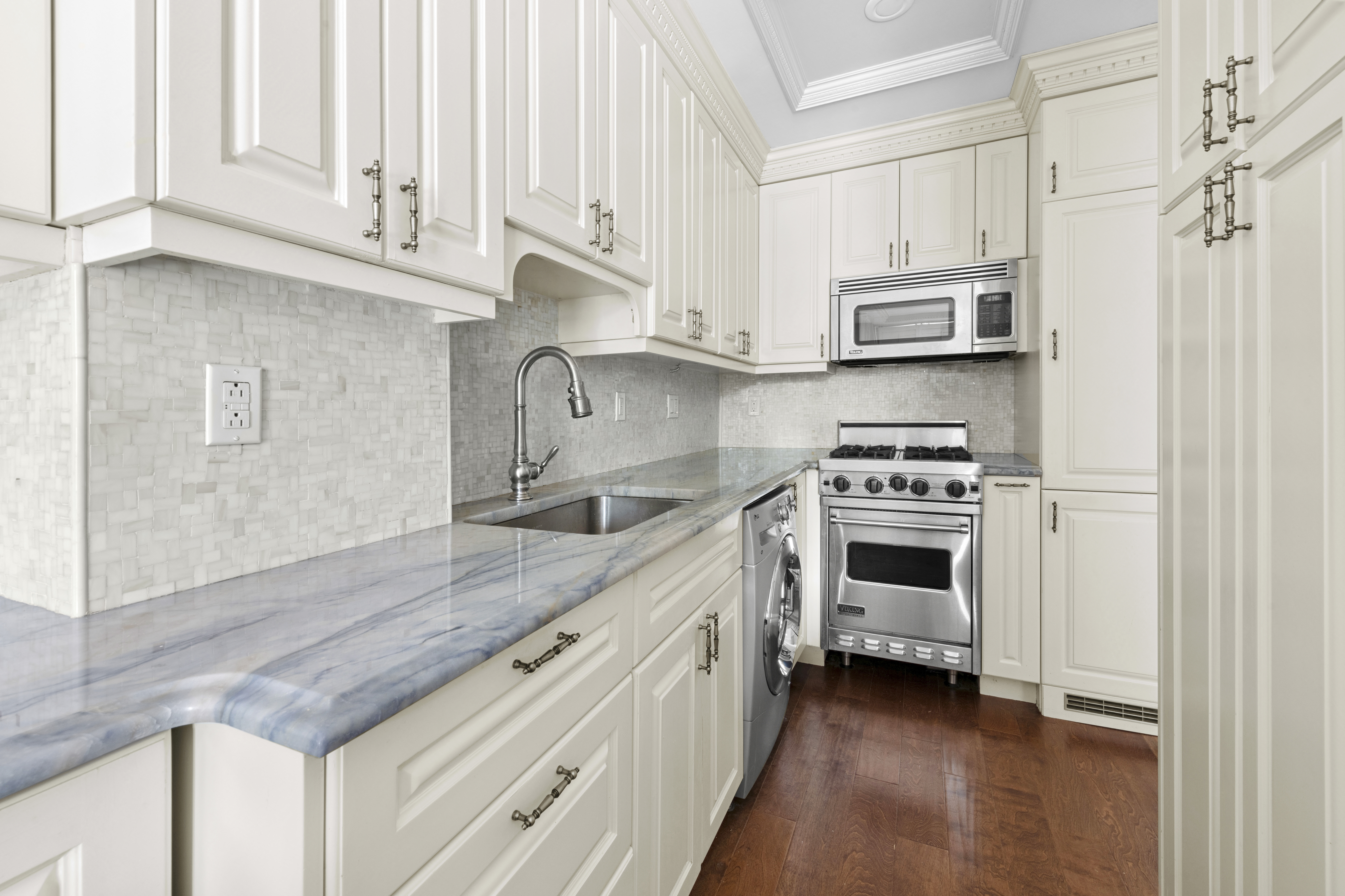 393 West 49th Street, Unit 5NN Manhattan, NY 10019 - Photo 5 of 13 a kitchen with stainless steel appliances white cabinets and a sink