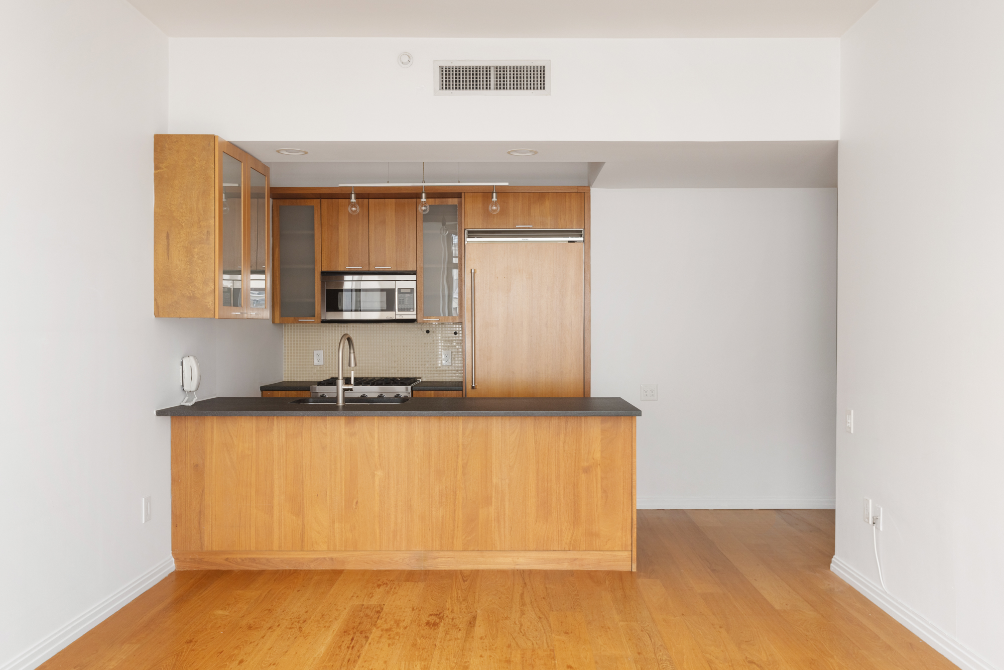 205 East 59th Street, Unit 10B Manhattan, NY 10022 - Photo 3 of 10 a kitchen with granite countertop wooden cabinets and stainless steel appliances