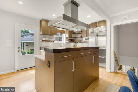 a kitchen with kitchen island a counter top space a sink stainless steel appliances and cabinets