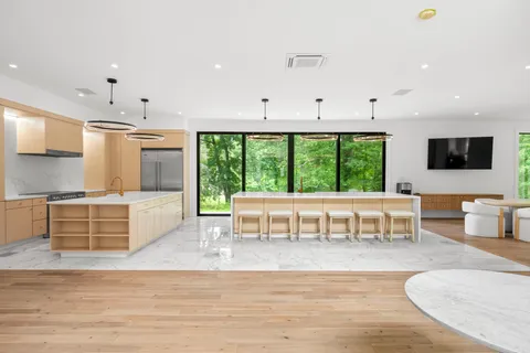 a view of kitchen with stainless steel appliances granite countertop a stove and white cabinets with wooden floor
