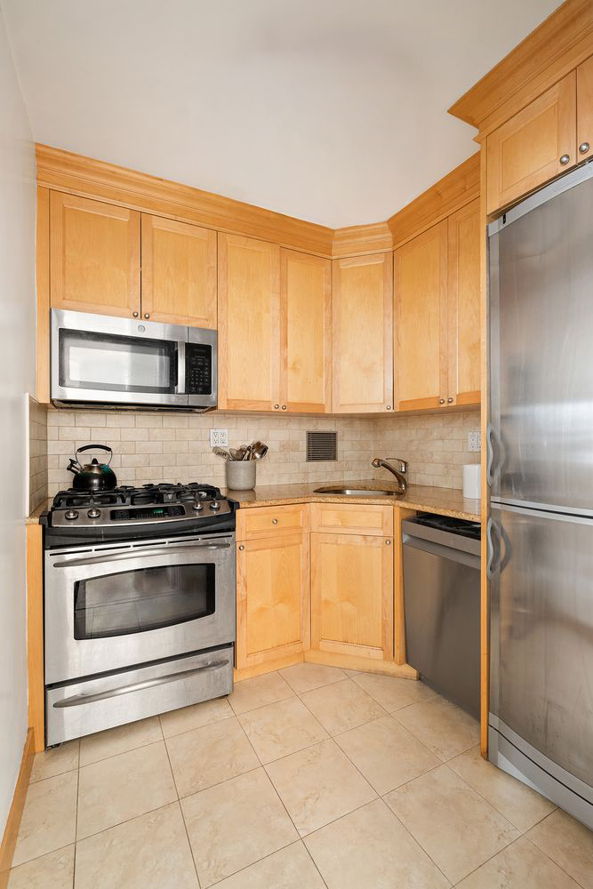201 East 77th Street, Unit 11E Manhattan, NY 10075 - Photo 4 of 6 a kitchen with a stove top oven cabinets and a refrigerator