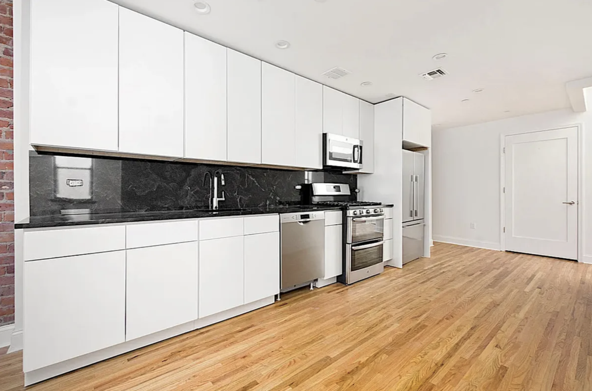 281 Grand Street, Unit 2R Manhattan, NY 10002 - Photo 2 of 5 a kitchen with stainless steel appliances granite countertop a sink a stove a microwave and white cabinets