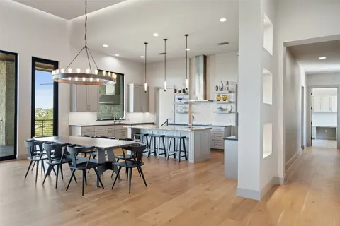 a kitchen with kitchen island granite countertop a stove a sink a dining table and chairs