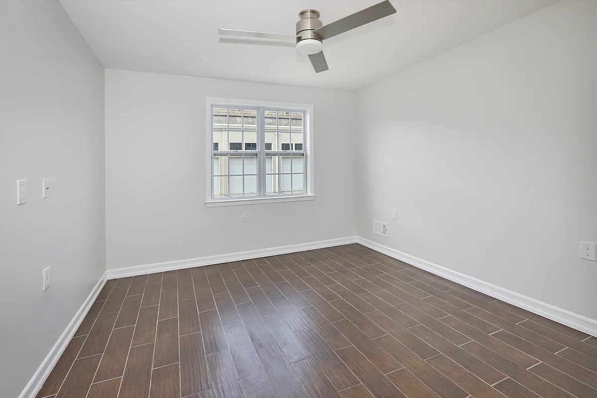 10220 Rockaway Beach Boulevard, Unit 1A Queens, NY 11694 - Photo 5 of 8 an empty room with wooden floor and windows
