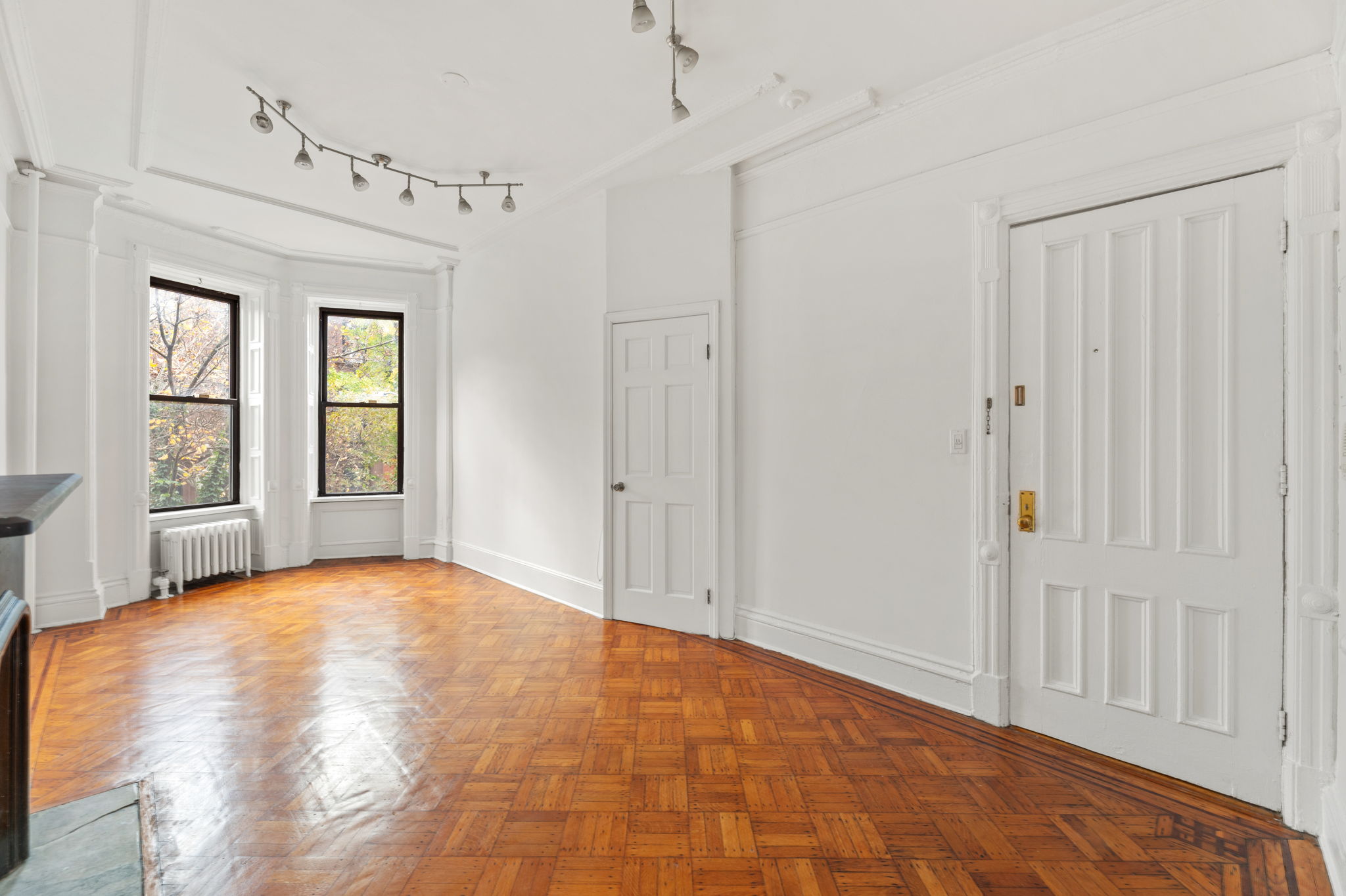 a view of an empty room with window and wooden floor