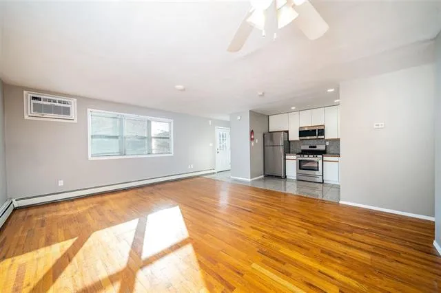 a view of kitchen and empty room with wooden floor