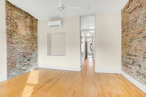 a view of empty room with wooden floor and bathroom