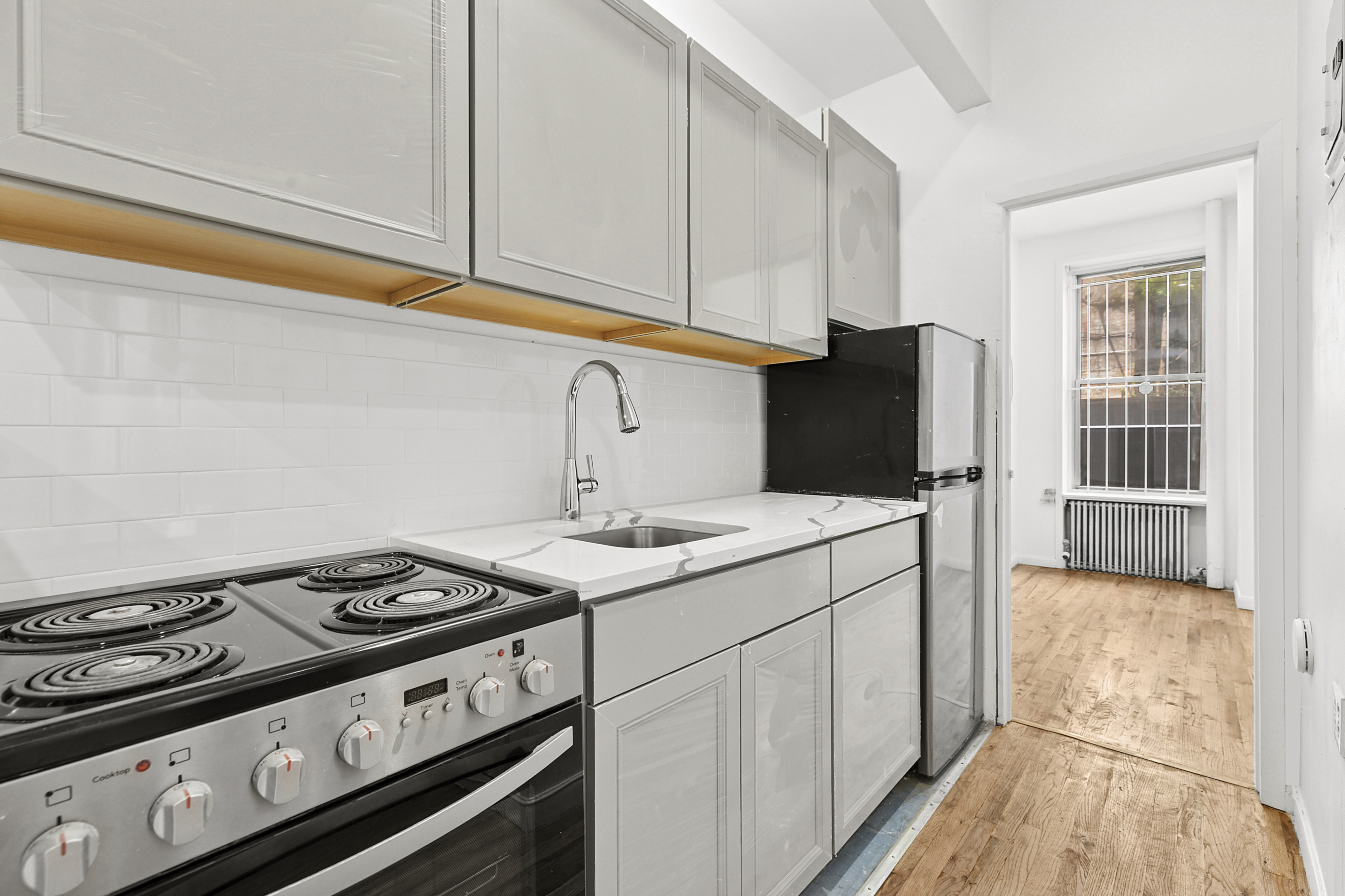 205 West 20th Street, Unit 1A Manhattan, NY 10011 - Photo 3 of 7 a kitchen with a stove and a refrigerator
