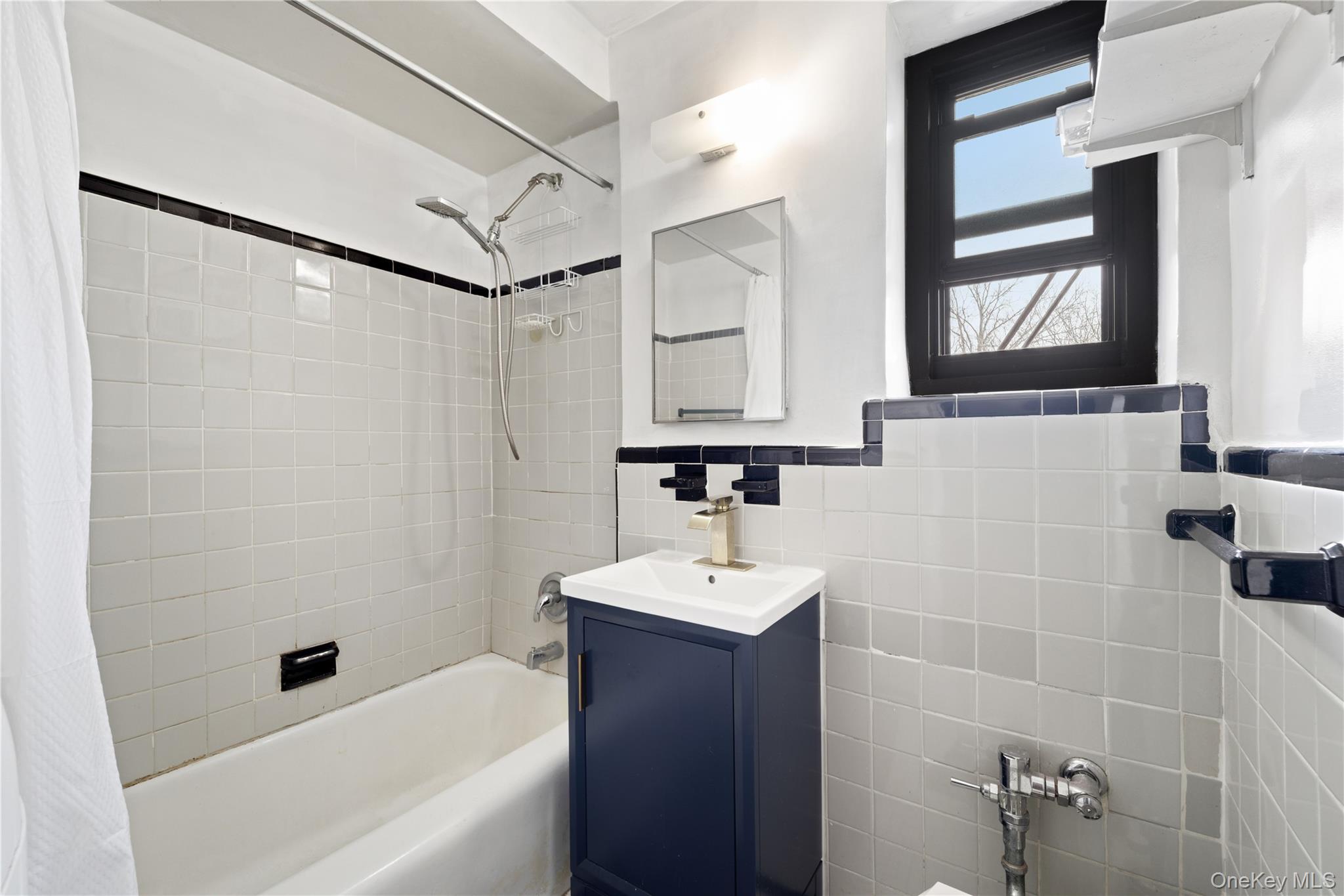 73-11 Bell Boulevard, Unit 2C Queens, NY 11364 - Photo 14 of 16 a bathroom with a sink a mirror and a bathtub