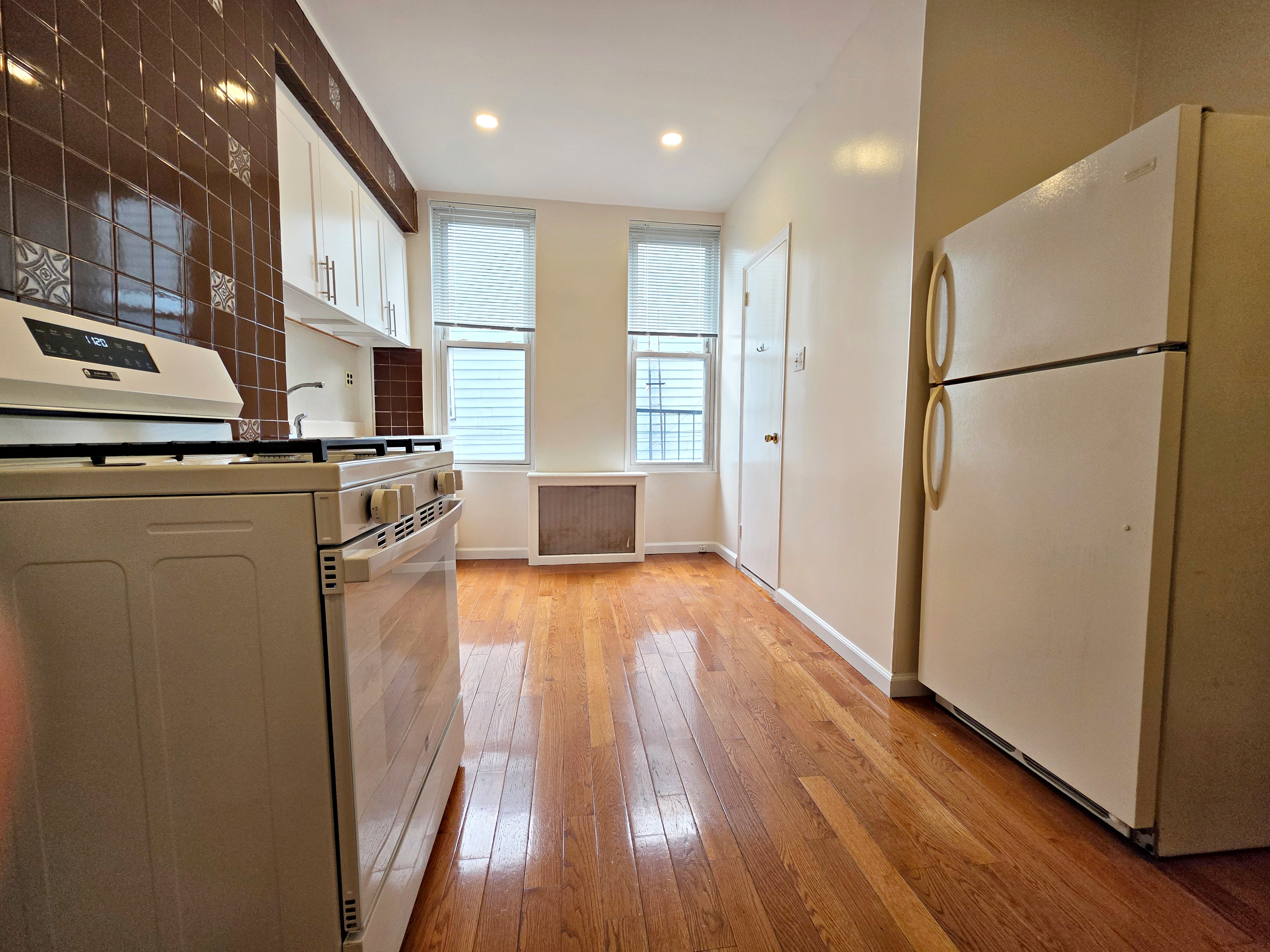 396 Manhattan Avenue, Unit 2L Brooklyn, NY 11211 - Photo 5 of 7 a kitchen with stainless steel appliances granite countertop a refrigerator a stove a sink and a microwave