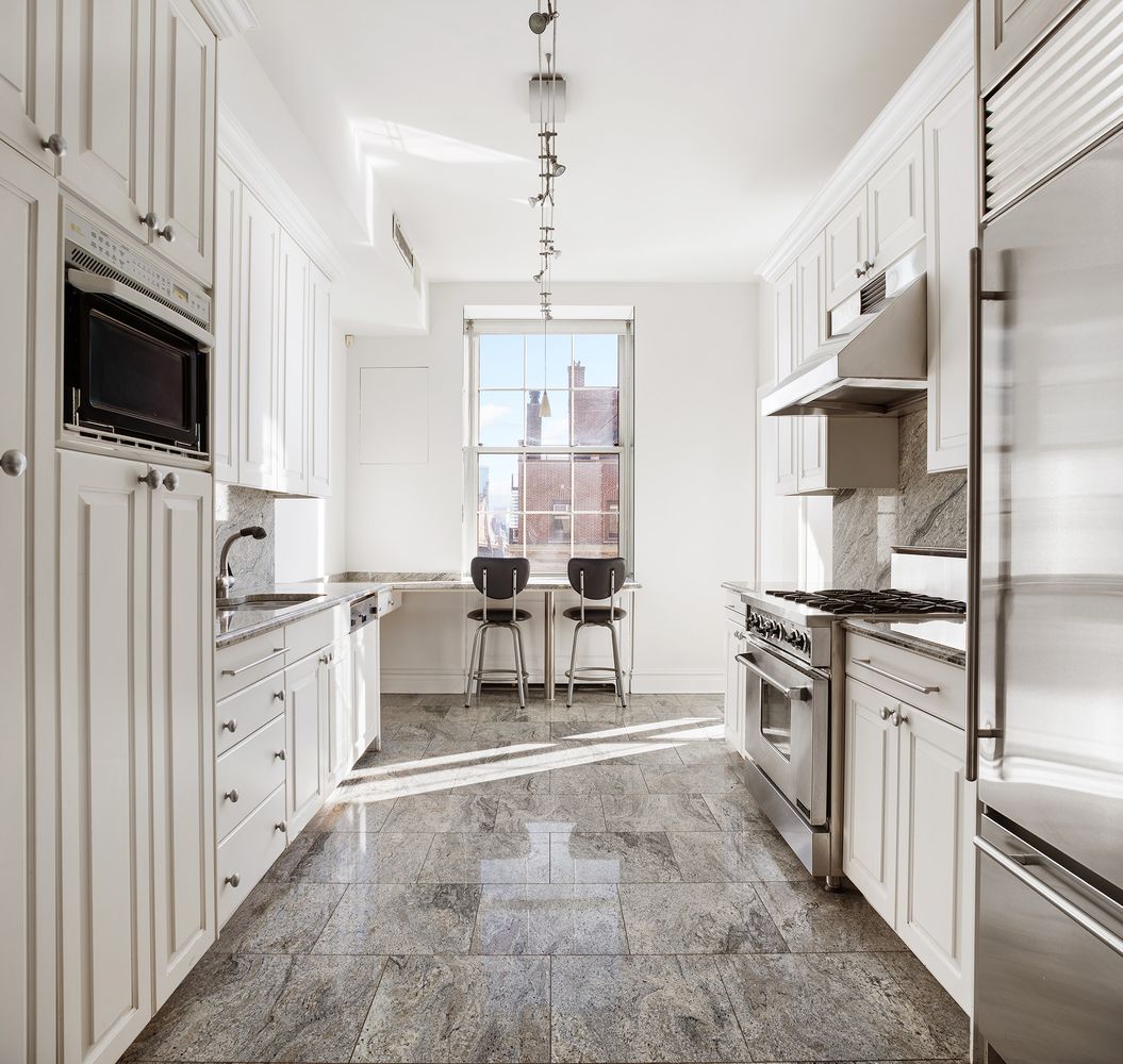 30 Sutton Place, Unit 14B Manhattan, NY 10022 - Photo 7 of 10 a kitchen with white cabinets and stainless steel appliances